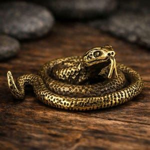 Könnte beinhalten: Detaillierte Messing-Schlangenfigur, auf einer Holzoberfläche aufgerollt. Die Schlange hat strukturierte Schuppen und eine gespaltene Zunge, wobei der Kopf erhoben ist. Die Figur hat eine goldene Farbe, und der Hintergrund ist unscharf.