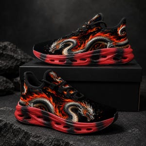 Könnte beinhalten: Ein Paar schwarze Sportschuhe mit einer detaillierten Grafik eines silbernen Drachen, der sich durch leuchtend orangefarbene und rote Flammen schlängelt. Die Schuhe haben schwarze Schnürsenkel und eine dicke, rote, strukturierte Sohle mit Ausschnitten.