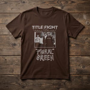 Puede incluir: Una camiseta de manga corta de color marr&oacute;n oscuro con un estampado gr&aacute;fico blanco. El dise&ntilde;o incluye el texto "TITLE FIGHT" sobre una fotograf&iacute;a rectangular en blanco y negro de cuatro personas, con "06 'FIORAL GREEN' 99" debajo.