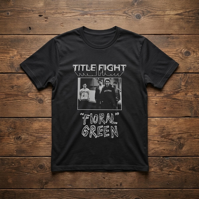 Puede incluir: Una camiseta negra de manga corta con un estampado gr&aacute;fico en blanco. El dise&ntilde;o incluye el texto "TITLE FIGHT" en la parte superior, una fotograf&iacute;a en blanco y negro de cuatro personas en el centro y el texto "FLORAL GREEN" en una fuente estilizada.