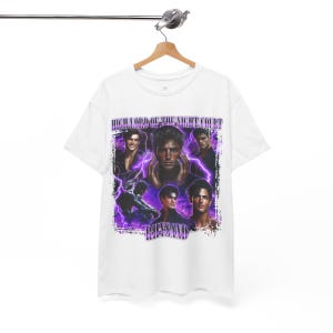 May include: White t-shirt featuring a graphic design with multiple images of a man, purple lightning bolts, and the text "HIGH LORD OF THE NIGHT COURT" and "RHYSAND". The design has a vintage aesthetic.