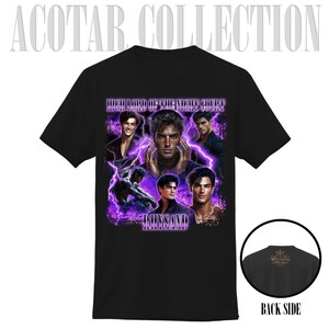 May include: Black t-shirt featuring a graphic design with the text "HIGH LORD OF THE NIGHT COURT" and the name "RHYSAND". The design includes multiple images of a man with purple lightning effects. The back of the shirt is also visible.