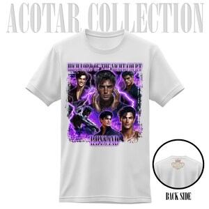 May include: White t-shirt featuring a collage of images with the text "HIGH LORD OF THE NIGHT COURT" and "RHYSAND" in purple. The back of the shirt has a small graphic and the words "BACK SIDE".