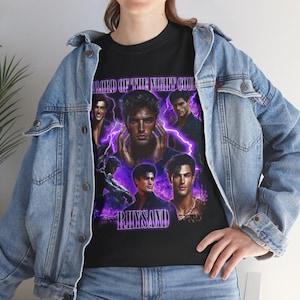May include: Black t-shirt featuring a collage of male figures with purple lightning effects. The text "LORD OF THE NIGHT COURT" and "RHYSAND" are displayed in a stylized font. The shirt is worn over a light blue denim jacket.