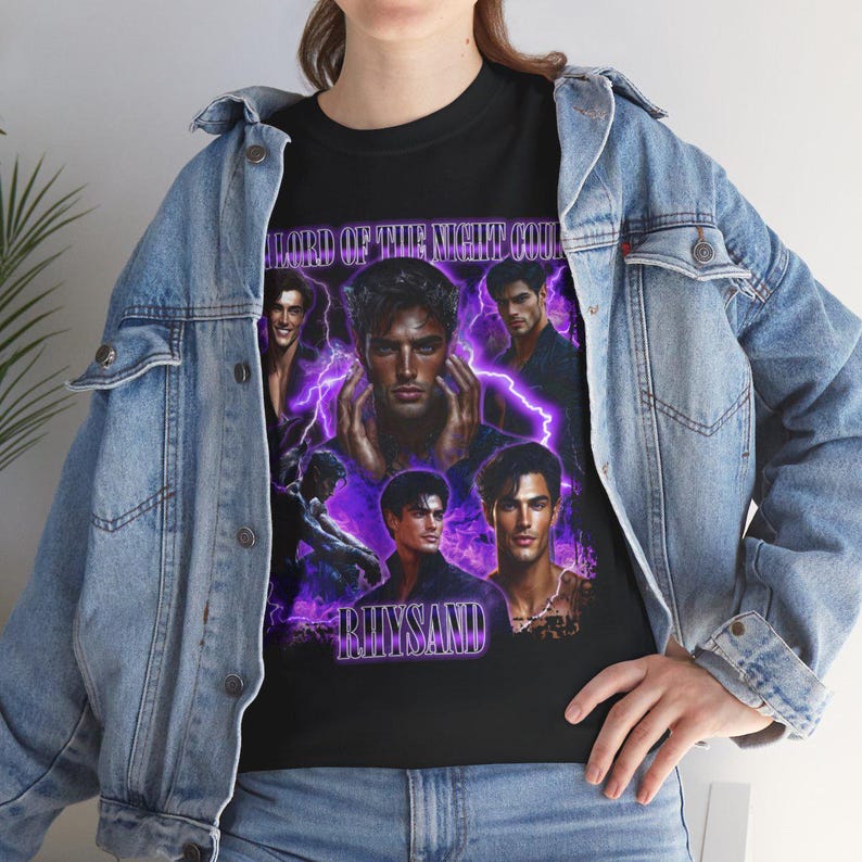 May include: Black t-shirt featuring a collage of male figures with purple lightning effects. The text "LORD OF THE NIGHT COURT" and "RHYSAND" are displayed in a stylized font. The shirt is worn over a light blue denim jacket.