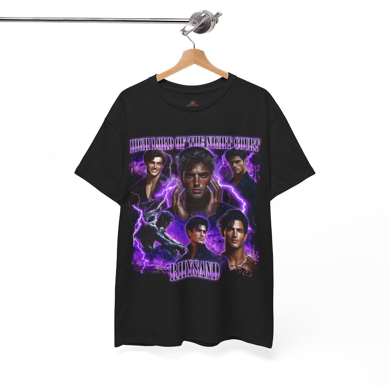 May include: Black t-shirt featuring a graphic design with multiple images of a person, purple lightning bolts, and the text "HIGH LORD OF THE NIGHT COURT" and "RHYSAND". The shirt is hanging on a wooden hanger.