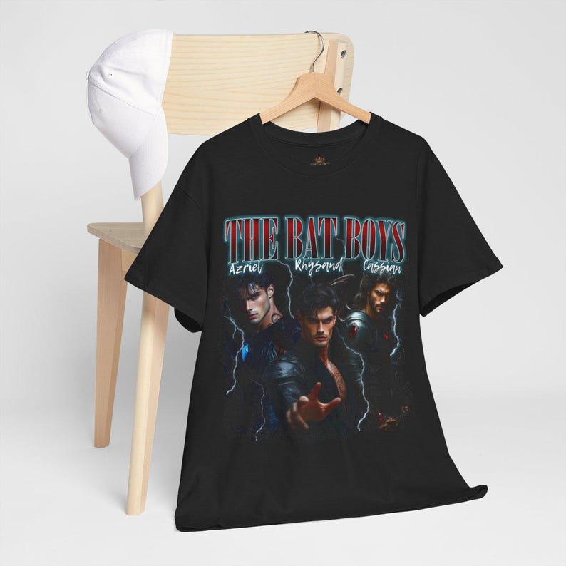 May include: Black t-shirt featuring the text "THE BAT BOYS" in a retro font, with the names Azriel, Rhysand, and Cassian below. The shirt displays a graphic of three men in dark clothing.