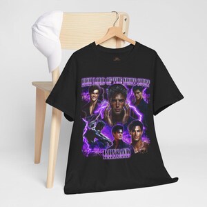 May include: Black t-shirt featuring a collage of images of a man with purple lightning and the text "HIGH LORD OF THE NIGHT COURT" and "RHYSAND". The shirt is hanging on a wooden hanger.