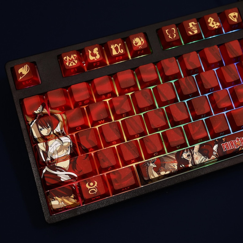 May include: A black mechanical keyboard with red keycaps. Some keycaps feature anime character illustrations and symbols. The keyboard has a Fairy Tail theme, with the logo visible on the spacebar. The keys are backlit with a rainbow glow.