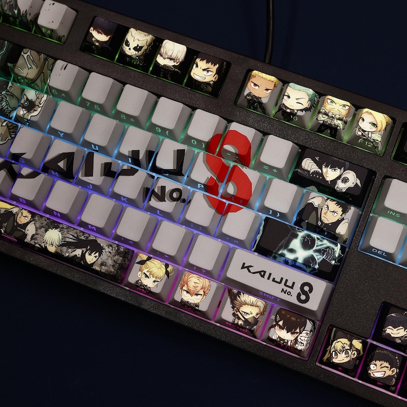 Op de afbeelding: Een zwart mechanisch toetsenbord met aangepaste keycaps met anime-karakterillustraties. Het toetsenbord heeft een rode "8"-toets en de tekst "KAIJU No. 8". De toetsen zijn verlicht met een regenboogverloop.