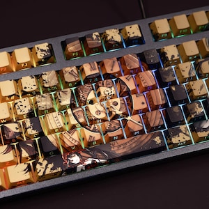 Może przedstawiać: Klawiatura mechaniczna z niestandardowymi nakładkami na klawisze w stylu steampunk i anime. Nakładki są złote, brązowe i czarne, ze szczegółowymi ilustracjami i tekstem. Klawiatura ma ciemnoszarą ramę i jest podświetlana kolorowymi diodami LED.