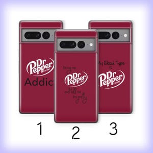 Può includere: Tre custodie per telefono bordeaux con il logo Dr. Pepper e frasi bianche. La prima custodia dice "Addic" con il logo. La seconda custodia dice "Bring me Dr. Pepper and tell me I'm pretty." La terza custodia dice "My Blood Type is Dr. Pepper."