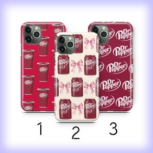 May include: Three phone cases with different designs. One case features a pattern of Dr. Pepper cups, another has Dr. Pepper cans and pink bows, and the third displays the Dr. Pepper logo. The cases are red and white.