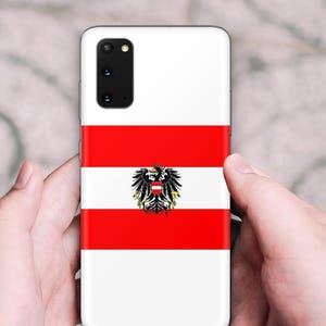 May include: A rectangular smartphone case featuring the Austrian flag design with horizontal red and white stripes and a central black eagle emblem. The case has a cutout for a multi-lens camera module in the upper left corner.