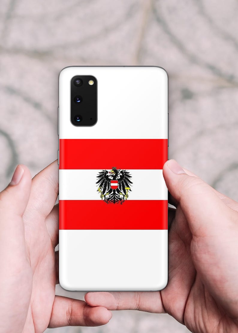 May include: A rectangular smartphone case featuring the Austrian flag design with horizontal red and white stripes and a central black eagle emblem. The case has a cutout for a multi-lens camera module in the upper left corner.