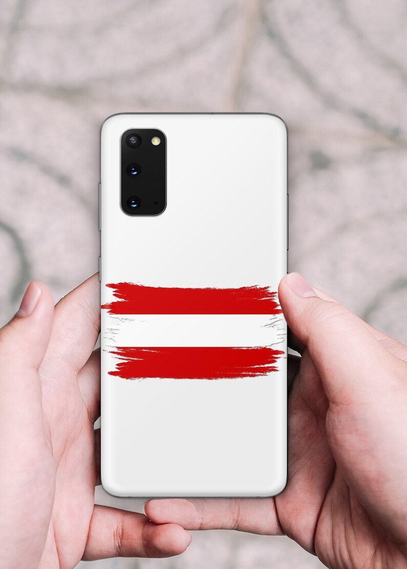 May include: A white smartphone case featuring a horizontal brushstroke design in red and white, mimicking the flag of Austria. The case has a rectangular camera cutout in the upper left corner with multiple lenses and a small circular flash component.