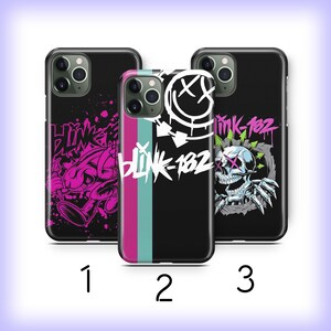 May include: Three black smartphone cases featuring Blink-182 designs. Case one has pink graffiti art. Case two displays a white smiley face logo and vertical stripes. Case three shows a skull graphic with green arrows and the text Blink-182.