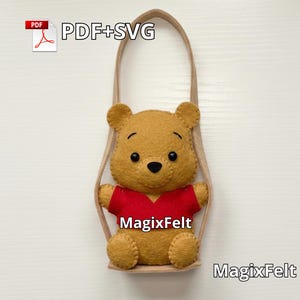 May include: A felt Winnie the Pooh plushie with a red shirt and black eyes. The plushie is in a tan swing with the text "PDF+SVG" and "MagixFelt".