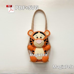 May include: A handmade orange and black felt Tigger-themed bag with a tan handle. The bag features Tigger's face and body, with black stripes and a pink nose. The text "PDF+SVG" and "MagixFelt" are visible.