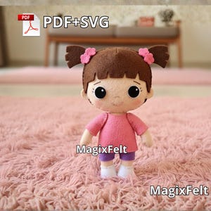 Könnte beinhalten: Eine handgefertigte Filzpuppe mit braunen Haaren in zwei Zöpfen, jeweils mit einer rosa Schleife. Die Puppe trägt ein rosa Hemd, lila Shorts und weiße Socken. Sie steht auf einem rosa, flauschigen Teppich. Der Text "PDF+SVG" und "MagixFelt" ist enthalten.