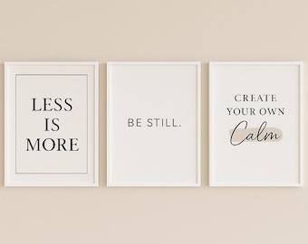 Puede incluir: Tres impresiones enmarcadas con texto minimalista. La primera dice "LESS IS MORE", la segunda "BE STILL." y la tercera "CREATE YOUR OWN Calm". Los marcos son blancos, sobre un fondo beige neutro.