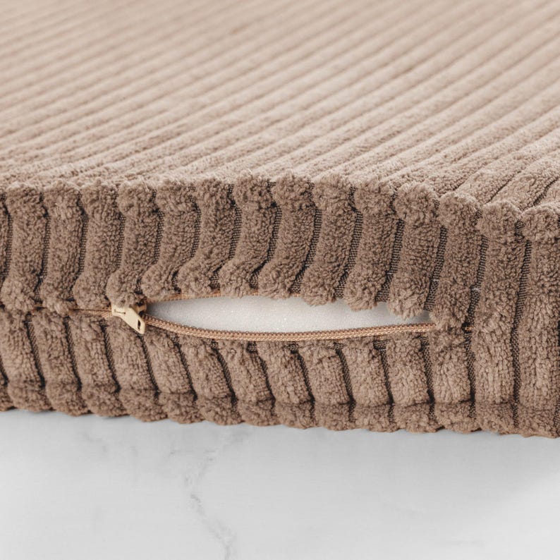 A close-up view of a brown, textured fabric with a zipper pull visible.