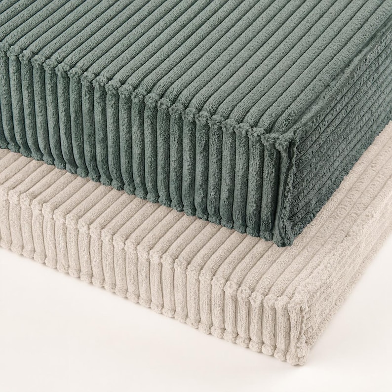 two rectangular cushions, one green and one beige, stacked on top of each other.