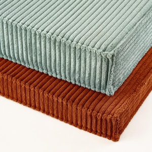two textured fabric pieces, one light blue and one dark brown, stacked on top of each other.