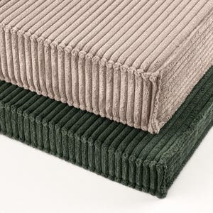 two rectangular cushions, one beige and one green, stacked on top of each other.