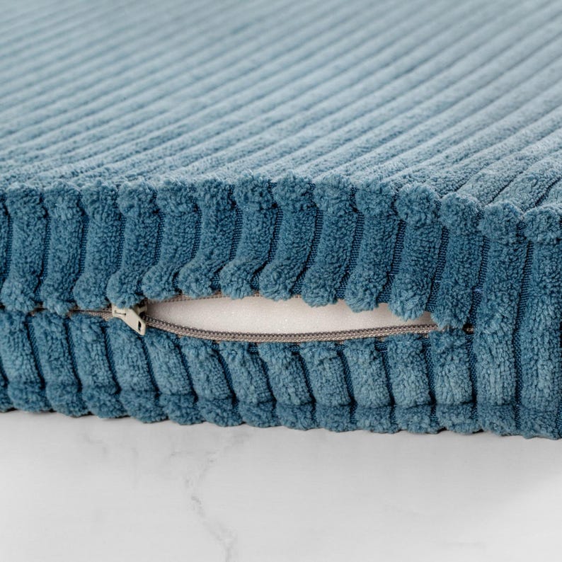 A close-up view of a blue, textured fabric with a zipper pull visible.