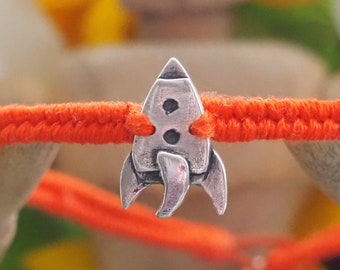 A cute unique tiny fine silver rocket on a beautiful orange leather, sterling silver and cotton woven charm bracelet...