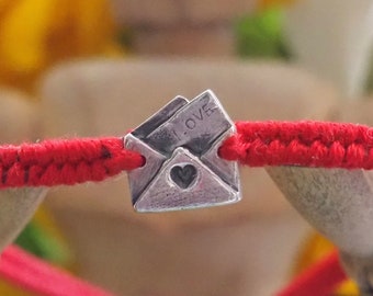 A lovely fine silver love letter hand made in fine silver on a beautiful red leather and cotton friendship bracelet...