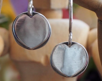 A pair of simple disc heart handmade in eco friendly fine silver heart earrings on handmade sterling silver wires.