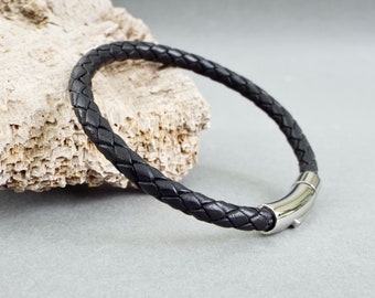 May include: A black leather bracelet with a braided design and a silver clasp.