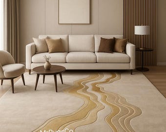 May include: Beige area rug featuring a flowing, river-like pattern in gold and tan hues. The rug is in a living room with a cream sofa, cushions, and a wooden coffee table. The text "MrRugsCo" is visible on the rug.