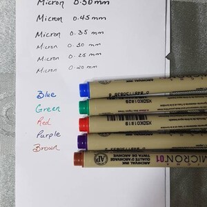 Puede incluir: Cinco bol&iacute;grafos de tinta de archivo de la marca Micron en azul, verde, rojo, morado y marr&oacute;n. Los bol&iacute;grafos est&aacute;n etiquetados con el tama&ntilde;o de la punta en mil&iacute;metros: 0,50 mm, 0,45 mm, 0,35 mm, 0,30 mm, 0,25 mm y 0,20 mm.