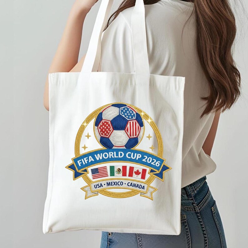 May include: White tote bag featuring a soccer ball design with the text "FIFA WORLD CUP 2026". The design includes the flags of the USA, Mexico, and Canada. The bag has two white handles.