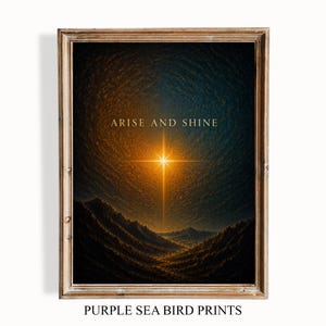 Può includere: Una stampa artistica incorniciata che raffigura un paesaggio scuro e strutturato sotto un cielo notturno vorticoso con una luminosa stella dorata al centro. Il testo ARISE AND SHINE è stampato in lettere dorate sopra la stella. Cornice in legno chiaro.