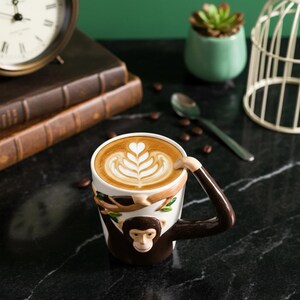 Puede incluir: Un juego de tres tazas de cerámica con un acabado mate moteado. Las tazas son de color crema, marrón claro y marrón oscuro. Cada taza tiene un diseño simple y minimalista y un asa redondeada.