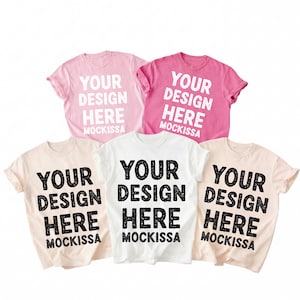 May include: Five t-shirts in various colors: light pink, hot pink, white, and two shades of beige. Each shirt has the text "YOUR DESIGN HERE MOCKISSA" printed in black or white, depending on the shirt color. The shirts are displayed on a white background.