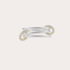 May include: A multi-band ring featuring three smooth, polished silver-toned bands that are held together by two circular, gold-toned side connectors. Each of the two side connectors is encrusted with a series of small, clear, sparkling stones.