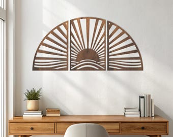 May include: A three-panel wooden wall art piece depicting a sunrise over water. The design features a semi-circular shape with radiating sun rays and wavy lines representing the water. The art is mounted on a white wall above a wooden desk.