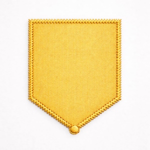 Puede incluir: Parche de tela amarilla en forma de escudo con base puntiaguda. El parche tiene una superficie texturizada y está delineado con una costura dorada en zigzag. Un pequeño botón redondo dorado está en la parte inferior.