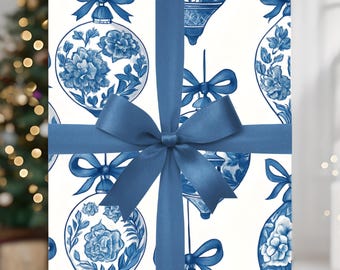 May include: A wrapped gift with a blue bow. The wrapping paper features a white background with a blue floral ornament pattern. The bow and ribbon are a solid blue color. A Christmas tree is visible in the background.