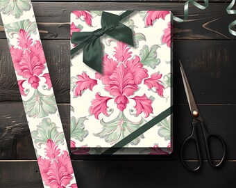 May include: A wrapped gift box with a dark green bow and ribbon, featuring a floral pattern in pink and green on an off-white background. A matching ribbon and scissors are also present on a dark wood surface.