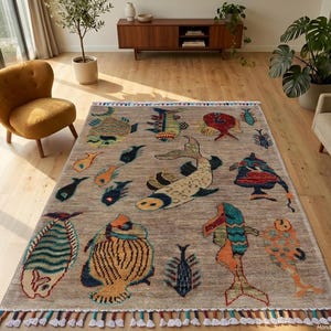 May include: A rectangular area rug with a light brown base featuring a variety of colourful fish illustrations in shades of blue, orange, yellow, and red. The rug has a fringed edge with multi-coloured tassels along the top and bottom borders.