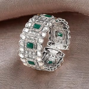 Peut inclure: Bracelet argenté au design géométrique. Le bracelet présente des pierres carrées vert émeraude et des accents clairs et étincelants. Le bracelet est en métal et possède un design articulé. Un bijou élégant.