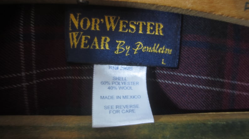 May include: A blue label with gold text that reads "Nor'Wester Wear By Pendleton" and "RN# 29685". The label also includes the text "Shell 60% Polyester 40% Wool", "Made in Mexico", "See Reverse for Care", and "L".