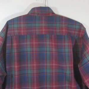 May include: A long-sleeved plaid shirt in shades of red, blue, green, and white. The shirt has a button-down collar and a button-up front.