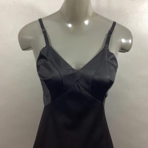 May include: A black satin slip dress with thin straps. The dress has a V-neckline and a fitted bodice.